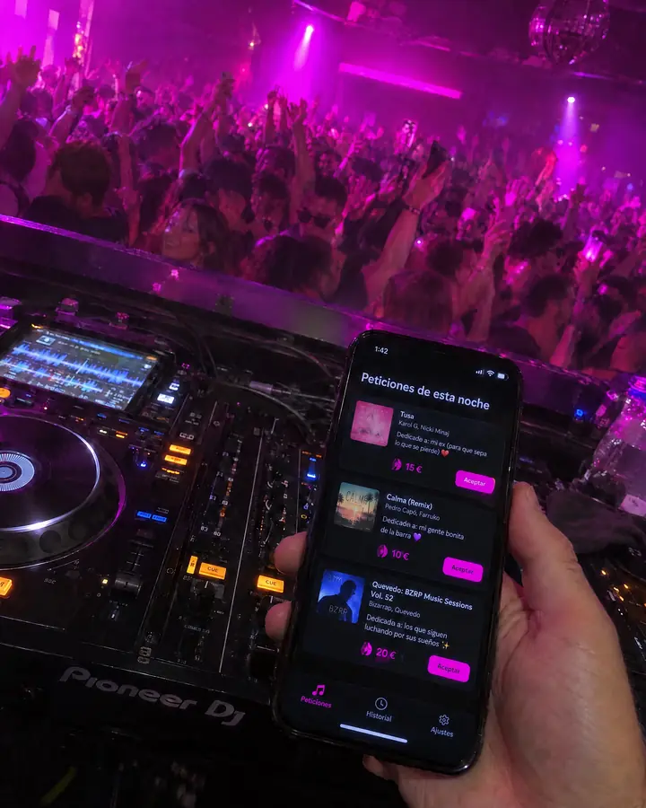 Desde dentro de la cabina, el DJ mira en su móvil las peticiones de esta noche con su dedicatoria y su propina, con la pista llena delante.