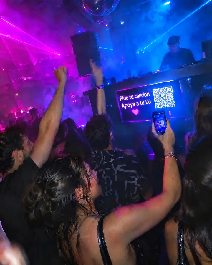La pista de una discoteca llena, con la cabina del DJ al fondo y móviles en alto.