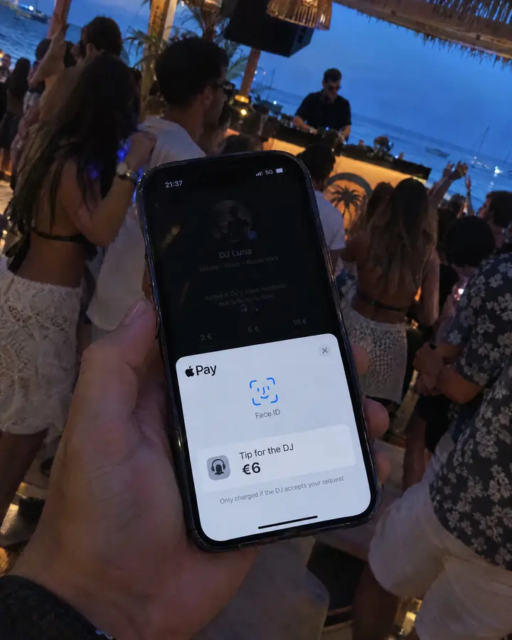 At a beach club, a phone shows the Apple Pay sheet with the tip for the DJ and the note that it is only charged if they accept.